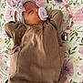 baby, infant, pacifier, headband, bow, blanket, floral_pattern, brown_sweater, clothing, cute, sleepwear, child, newborn, lying_down, indoors, soft_toys, comfort, pastel_colors, pink, white