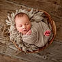 newborn, baby, sleeping, wrapped, wooden_bowl, fluffy_wool, cozy, infant, peaceful, soft, portrait, closeup, indoors, cute, child, resting, wrapped_in_cloth, floor, natural_light, calm