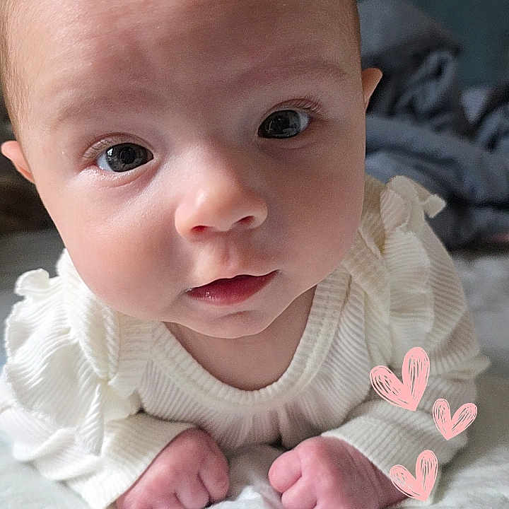 Raeleighana is registered to the contest to win money with this photo: baby, infant, face, eyes, hands, white_clothing, lying_down, soft_surface, indoor, portrait, cute, curious, skin, head, expression, fist, heart_doodles, closeup, child, newborn