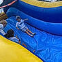 children, inflatable_slide, outdoor, play, fun, boy, cap, tshirt, shorts, socks, smile, happy, summer, activity, recreation, group, friends, blue, yellow, cloudy_sky