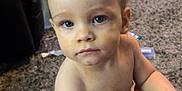 Monte is registered to the contest to win money with this photo: toddler, child, baby, blue_eyes, indoor, carpet, baby_swing, leather, hand, living_room, furniture, floor, curious, face, skin, person, expression, messy, room, young_child