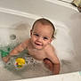 toddler, bath, bubble_bath, toy, yellow_toy, bathtub, child, foam, water, smile, happy, skin, young_child, blue_eyes, wet_hair, bathroom, playing, sitting, cute, bubble