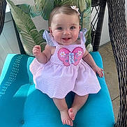 Layla Faith joined the competition — help win amazing prizes! baby, child, smiling, pink_dress, butterfly, wicker_chair, cushion, indoor, happy, cute, infant, person, portrait, seated, blue_cushion, hair_clip, small_feet, cheerful, bright, sunlight