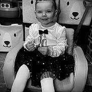 Lola participe au concours pour gagner de l'argent avec cette photo : accessories, bodypart, chair, child, clothing, couch, face, female, finger, formalwear, furniture, girl, hand, head, person, photography, portrait, shorts, sitting, tie