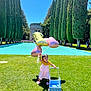 toddler, child, balloons, number_balloon, pink_dress, toy_stroller, grass, outdoor, sunny, trees, cypress_trees, reflecting_pool, blue_sky, shoes, play, summer, greenery, nature, happy, walking