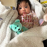 Genesis is registered to the contest to win money with this photo: baby, infant, blanket, teddy_bear, clothing, child, cute, portrait, indoors, soft_texture, sleepwear, toy, face, person, warm, cozy, newborn, expression, snuggled, little_sister