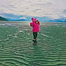 beach, boots, child, cloudy_sky, cold_weather, horizon, isolated, landscape, mountains, nature, outdoor, pink_jacket, ripples, sand, scenic, spring, standing, text_overlay, water, winter_clothing