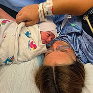 Aria joined the competition — help win amazing prizes! newborn, baby, adult, hospital, hospital_gown, blanket, bed, glasses, hand, person, medical_bracelet, infant, face, resting, parent, healthcare, closeup, skin, tenderness, indoor