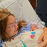 mother, newborn, baby, hospital_bed, blanket, glasses, hospital_gown, medical_equipment, bed_pillow, infant, parent, love, care, family, rest, healthcare, new_life, indoor, person, portrait