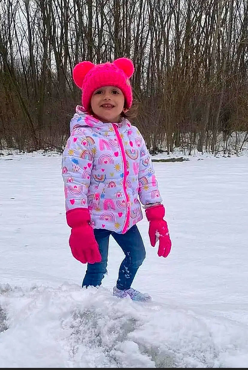 Holland is registered to the contest to win money with this photo: baby_toddler_clothing, cap, child, freezing, fun, headwear, hood, ice_cap, jacket, joy, knit_cap, magenta, people_in_nature, person, pink, playing_in_the_snow, recreation, sleeve, smile, snow
