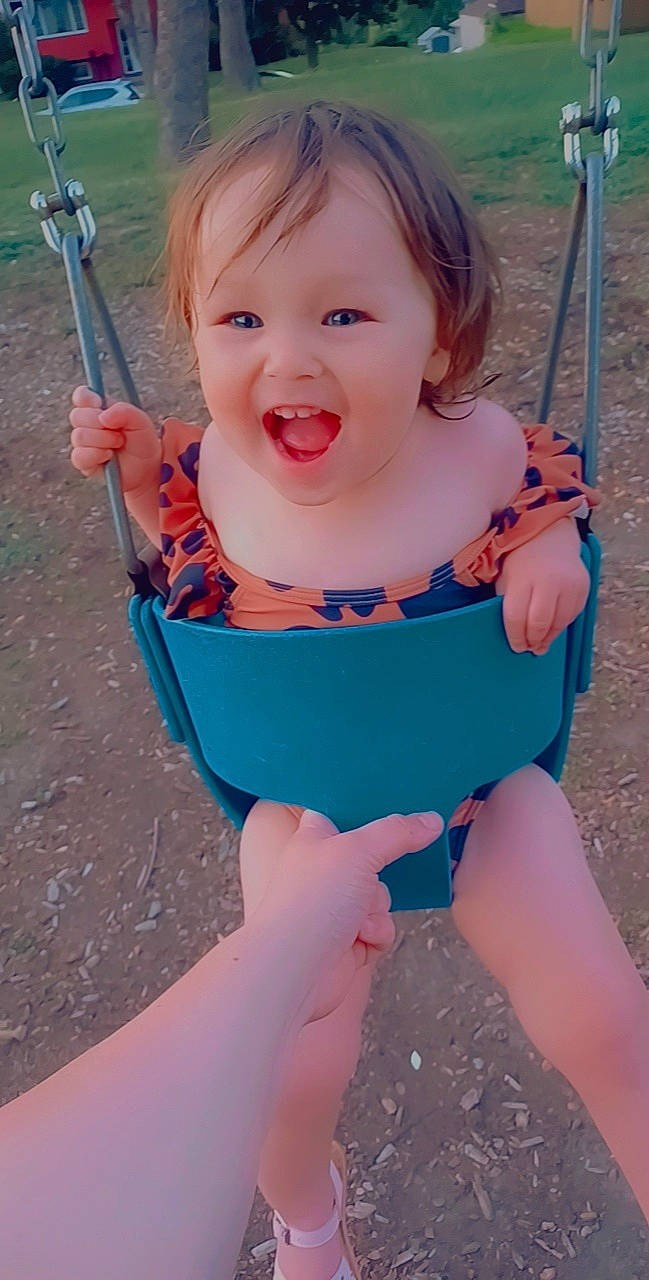 Haylie is registered to the contest to win money with this photo: azure, baby, baby_toddler_clothing, blue, cheek, eye, face, finger, happy, head, human_body, iris, lip, organ, person, pink, skin, smile, standing, swing