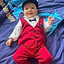 baby, child, infant, red_clothing, vest, pants, white_shirt, bow_tie, cap, socks, smiling, face, blue_blanket, lying_down, indoor, cute, happy, portrait, person, young