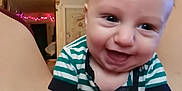 Lucas joined the competition — help win amazing prizes! baby, infant, smiling, happy, striped_shirt, hands, face, indoors, warm_lighting, string_lights, cheerful, cute, closeup, person, toddler, child, expression, skin, head, eyes
