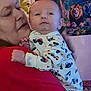 baby, adult, holding, onesie, vehicle_pattern, red_shirt, face, portrait, indoor, poster, jungle_theme, lion, giraffe, colorful, person, child, hand, clothing, wall, closeup