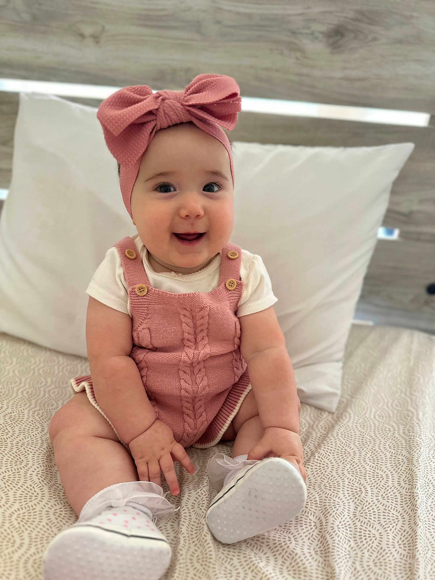 Maya joined the competition — help win amazing prizes! baby, infant, smiling, pink_bow, headband, knitted_romper, white_shirt, white_shoes, socks, bed, pillow, blanket, chubby_arms, chubby_legs, cute, happy, indoors, portrait, person, child