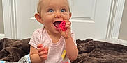 Kinsley is registered to the contest to win money with this photo: toddler, child, baby, toy, pink_ball, smiling, happy, sitting, indoor, blanket, brown_blanket, water_bottle, casual_clothing, shorts, tshirt, pigtails, blue_eyes, door, floor, playtime