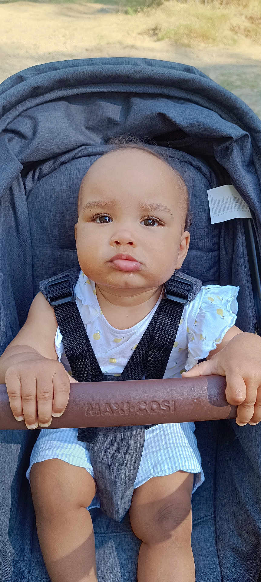 Romy a rejoint le concours — aidez-le/la à gagner de superbes lots ! baby, child, stroller, seatbelt, outdoor, sunlight, expression, grip, clothing, infant, face, person, seat, handlebar, cute, young, summer, skin, hands, legs