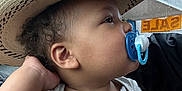 Amir joined the competition — help win amazing prizes! toddler, child, pacifier, hat, straw_hat, car_interior, window, raindrops, shirt, animal_print, sale_sign, side_profile, curly_hair, casual_clothing, hand, looking_away, indoors, daylight, cute, portrait