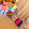 child, girl, smiling, pink_dress, indoor, gift_bags, presents, colorful, polka_dots, birthday, living_room, curtains, tile_floor, furniture, flowers, tissue_paper, portrait, standing, happy, social_media_screenshot