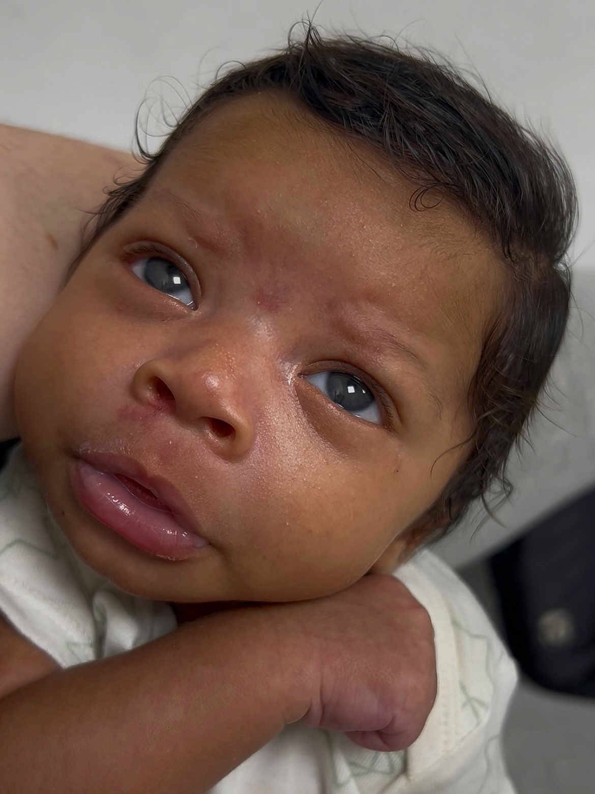 Kylan joined the competition — help win amazing prizes! baby, closeup, face, infant, skin, hand, curly_hair, eyes, expression, portrait, newborn, child, person, cute, soft_lighting, clothing, indoor, resting, young, peaceful