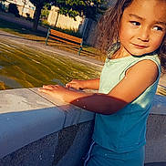 Anton participe au concours pour gagner de l'argent avec cette photo : child, curly_hair, water_fountain, outdoor, park, bench, tree, sunlight, shadow, summer_clothing, blue_shorts, blue_shirt, side_view, kneeling, thoughtful_expression, daytime, nature, skin, person, casual