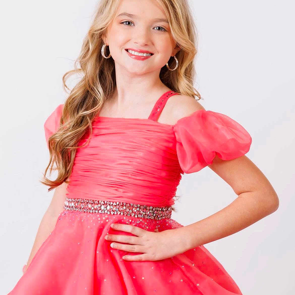 Avery joined the competition — help win amazing prizes! child, girl, dress, pink, smile, portrait, long_hair, curly_hair, earrings, posing, fashion, young, sparkle, glamour, studio, white_background, happy, confident, hand_on_hip, cute