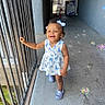 Tarranae is registered to the contest to win money with this photo: toddler, child, smiling, dress, bow, hair, bubbles, footwear, corridor, railing, concrete, outdoor, sunlight, happy, walking, person, baby, blue, pattern, playful