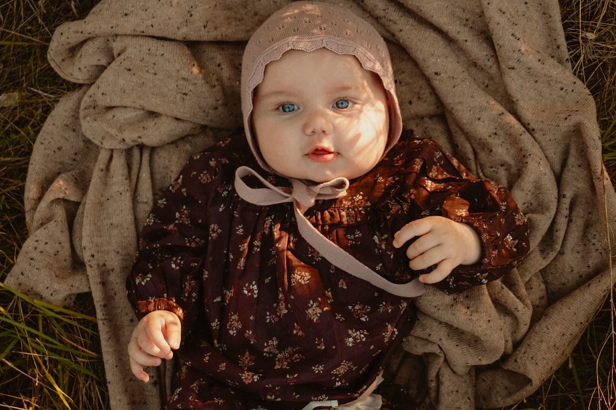 Lottie is registered to the contest to win money with this photo: adaptation, baby, cheek, dress, face, facial_expression, grass, hat, head, headwear, mammal, outerwear, people_in_nature, person, plant, skin, sleeve, textile, toddler, tree