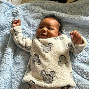 Genesis is registered to the contest to win money with this photo: baby, blanket, blue_blanket, child, clothing, cozy, cute, face, hand, happy, indoors, infant, lying_down, mickey_mouse_pattern, newborn, pajamas, person, skin, smiling, soft_texture