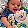 baby, bed, blanket, blue_shirt, brown_hair, child, close_up, colorful, cozy, face, finger, fleece, hand, happy, indoor, infant, lying_down, photography, portrait, smiling