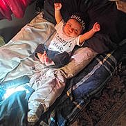 Dalen joined the competition — help win amazing prizes! newborn, baby, infant, child, portrait, lying_down, smiling, face, arms_raised, clothing, hat, blanket, bed, pillow, indoors, home, text_on_clothing, soft_lighting, carpet, family