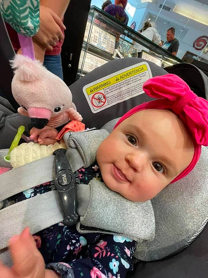 Harper is registered to the contest to win money with this photo: baby, baby_carriage, baby_products, baby_toddler_clothing, beanie, cap, car_seat, cheek, child, fashion_accessory, fun, headwear, knit_cap, nail, organ, person, pink, sitting, skin, smile