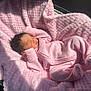 newborn, baby, infant, sleeping, pink_blanket, pink_outfit, onesie, soft_texture, fluffy_blanket, sunlight, shadow, face, hair, portrait, cute, peaceful, indoor, resting, baby_carrier, closeup