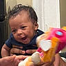 Nymir joined the competition — help win amazing prizes! baby, child, infant, smiling, happy, face, portrait, toy, stuffed_animal, colorful, indoor, home, sitting, supported, hands, caregiver, blue_shirt, curly_hair, close_up, family