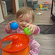 Willow joined the competition — help win amazing prizes! toddler, child, baby, sitting, playing, toys, balls, stacking_toy, smiling, face, portrait, indoors, playroom, floor, wood_floor, pink_pajamas, blonde_hair, hands, colorful, furniture