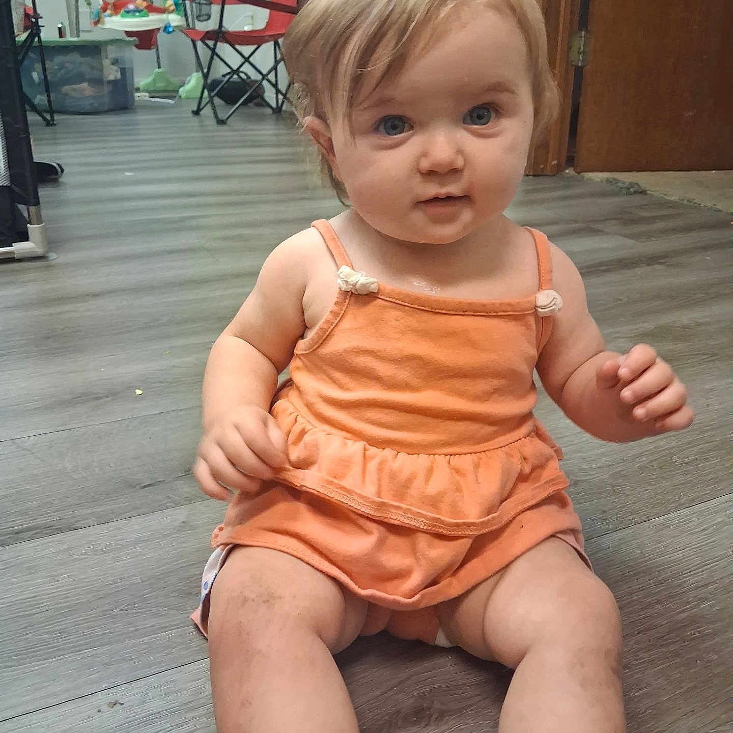 Willow joined the competition — help win amazing prizes! baby, child, infant, sitting, portrait, face, blue_eyes, blonde_hair, smiling, indoors, playroom, wood_floor, orange_outfit, dress, toy, high_chair, folding_chair, home, floor, photography