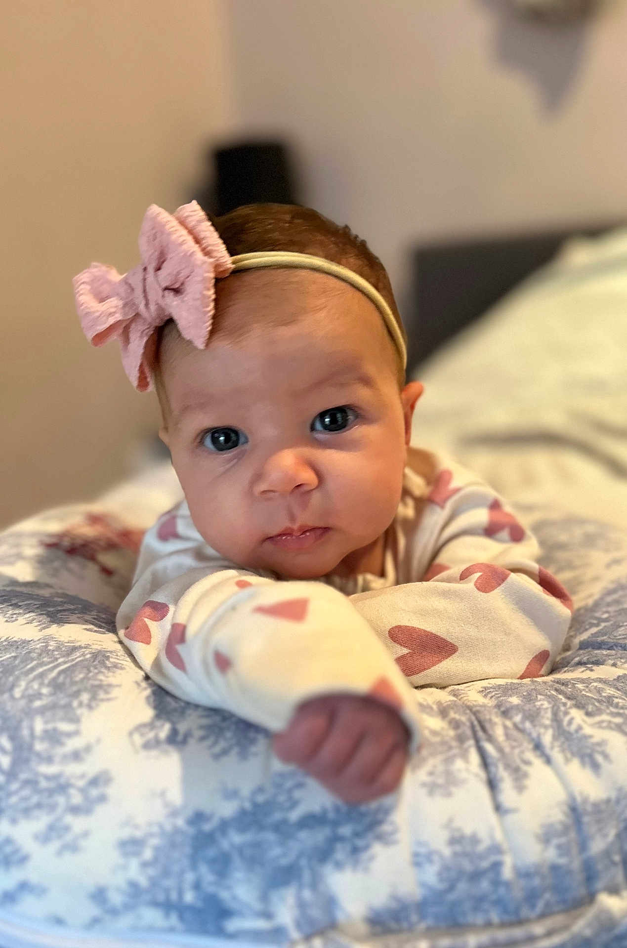 Arabella joined the competition — help win amazing prizes! baby, infant, headband, bow, cushion, pattern, hand, face, eyes, clothing, cute, portrait, indoor, child, expression, resting, soft, young, person, focus
