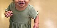 Mia is registered to the contest to win money with this photo: toddler, child, smiling, pigtails, green_dress, white_shoes, indoor, floor, person, happy, cute, young_child, standing, portrait, hair, face, skin, eyes, clothing, fun