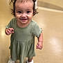 toddler, child, smiling, pigtails, green_dress, white_shoes, indoor, floor, person, happy, cute, young_child, standing, portrait, hair, face, skin, eyes, clothing, fun