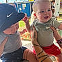baby, child, infant, toddler, smiling, hat, clothing, shorts, outdoor, daylight, tattoo, person, hand, playful, carnival, ferris_wheel, table, candy, happy, fun