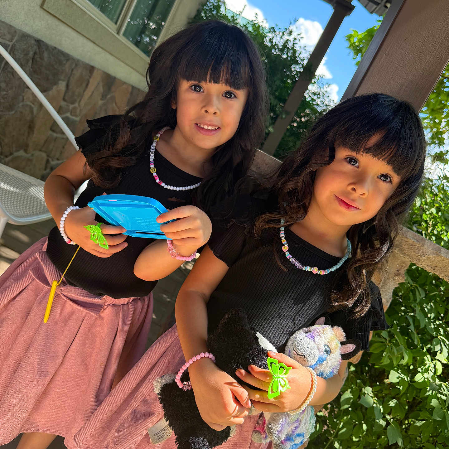 Ashley Y Grace joined the competition — help win amazing prizes! black_top, bracelet, child, curly_hair, cute, friendship, girl, greenery, happy, holding, necklace, outdoor, pink_skirt, playful, porch, portrait, smile, stone_wall, sunlight, toy