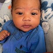 Ajani is registered to the contest to win money with this photo: baby, infant, blue_onesie, face, eyes, hand, blanket, soft, cute, newborn, portrait, indoors, clothing, expression, person, child, cozy, black_hair, skin, lying_down