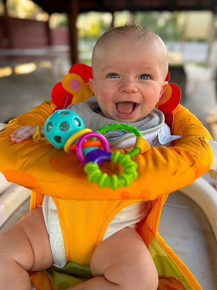 James Baby Jam is registered to the contest to win money with this photo: baby, child, smiling, happy, blue_eyes, infant, orange_seat, toy, colorful_toys, cheerful, cute, sitting, indoor, portrait, face, close_up, chubby_legs, playful, baby_seat, joyful