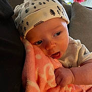 James Baby Jam is registered to the contest to win money with this photo: baby, infant, hat, blanket, couch, arm, face, hand, indoors, cozy, clothing, soft, cute, child, portrait, resting, comfort, expression, snuggle, warm