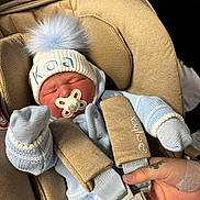 Koa joined the competition — help win amazing prizes! newborn, baby, car_seat, pacifier, blue_clothing, knitwear, hat, pom_pom, sleeping, infant, hand, tattoo, seat_belt, safety, child, cozy, indoor, person, cute, warm