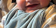 Koa is registered to the contest to win money with this photo: baby, smile, face, bib, onesie, blanket, couch, cozy, happy, infant, child, closeup, indoor, soft, pattern, person, cute, skin, head, expression
