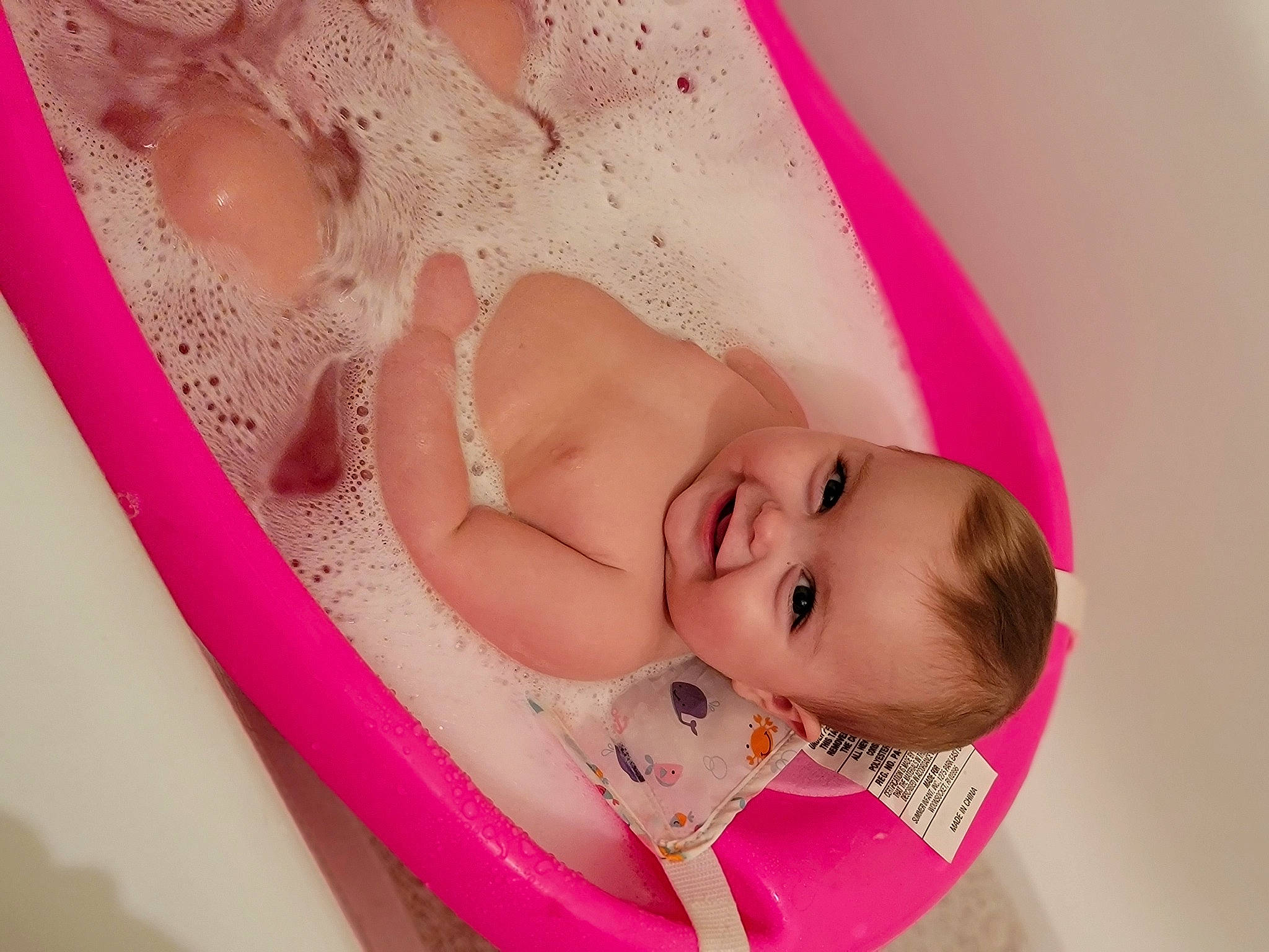 Kimberlynn is registered to the contest to win money with this photo: arm, baby, baby_products, baby_toddler_clothing, bathing, cheek, child, dress, eyebrow, eyelash, hair_accessory, happy, head, headgear, headpiece, human_body, joy, lip, person, pink