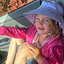 child, girl, hat, pink_jacket, sequins, smile, sunlight, car_seat, car_interior, window, legs, sitting, casual_clothing, happy, outdoor_light, nature_background, footwear, shorts, portrait, daylight