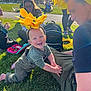 Jasper is registered to the contest to win money with this photo: baby, sunflower_headband, grass, outdoor, smiling, adult, people, sunlight, park, pinwheel, backpack, happy, crawling, headwear, nature, family, relaxing, daytime, colorful, playful