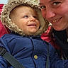 toddler, child, adult, smile, jacket, hood, outdoor, building, happy, face, person, winter_clothing, closeup, bonding, family, daylight, candid, warmth, interaction, blue_jacket